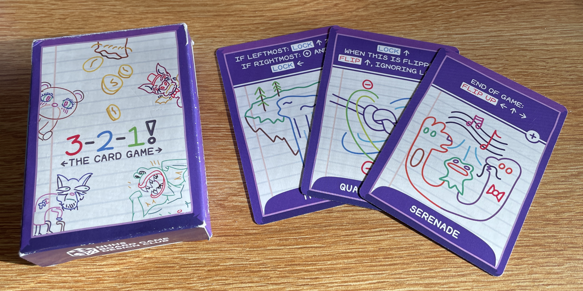 Box packaging and three cards, professionally printed, on a table.